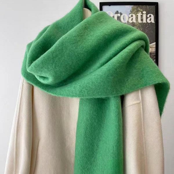 Green scarf with fringe wrapped around neck front view