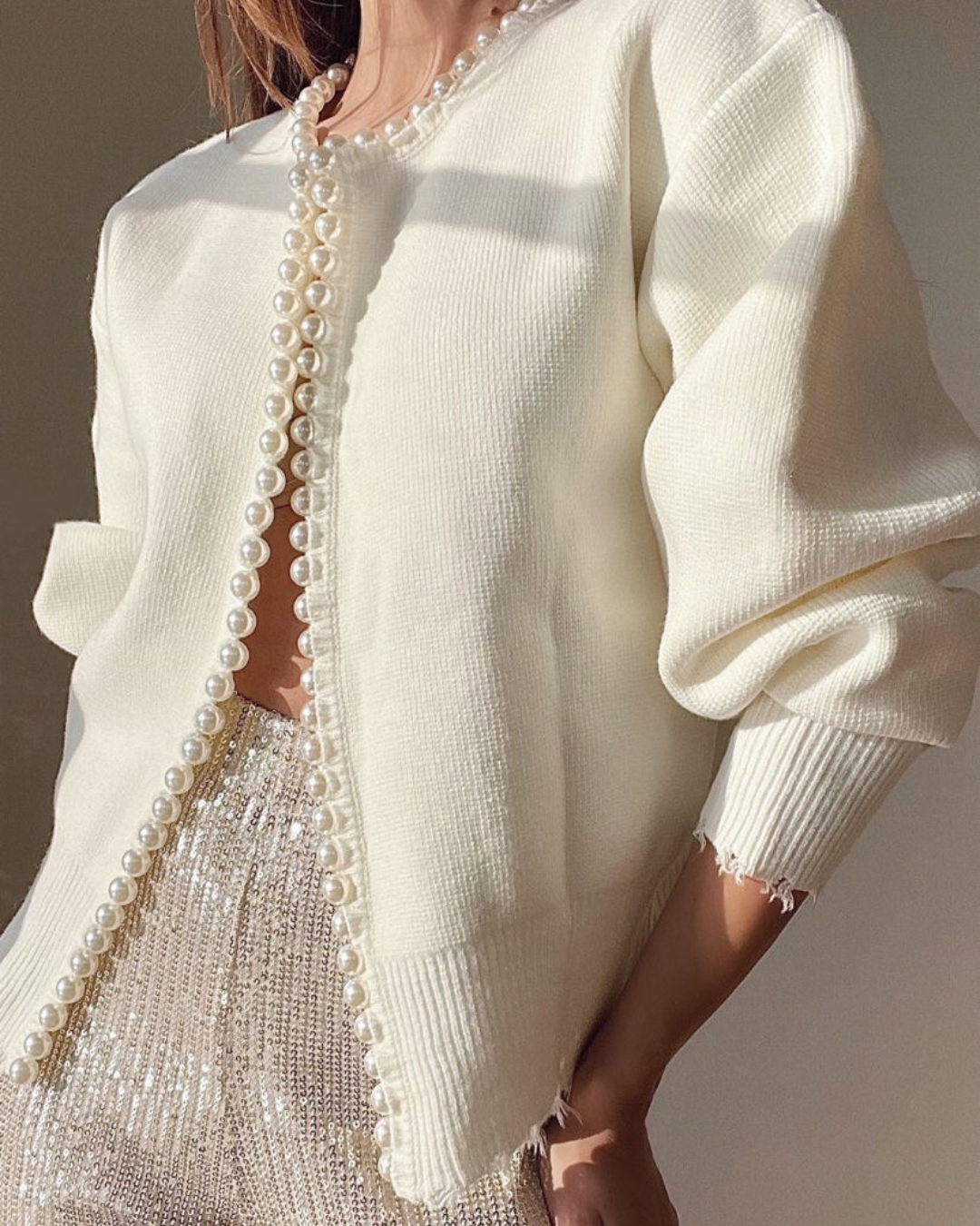 Cream cardigan with pearl trim worn over sequined skirt, front view
