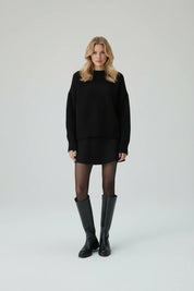 Black knit set with flared skirt and knee-high boots front view