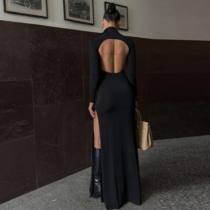 Black maxi dress with high collar and thigh-high slit, side view with handbag