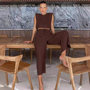 Brown two-piece set with crop top and wide-leg pants seated pose