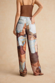Model showcasing patchwork jeans with distressed patches and brown top back view