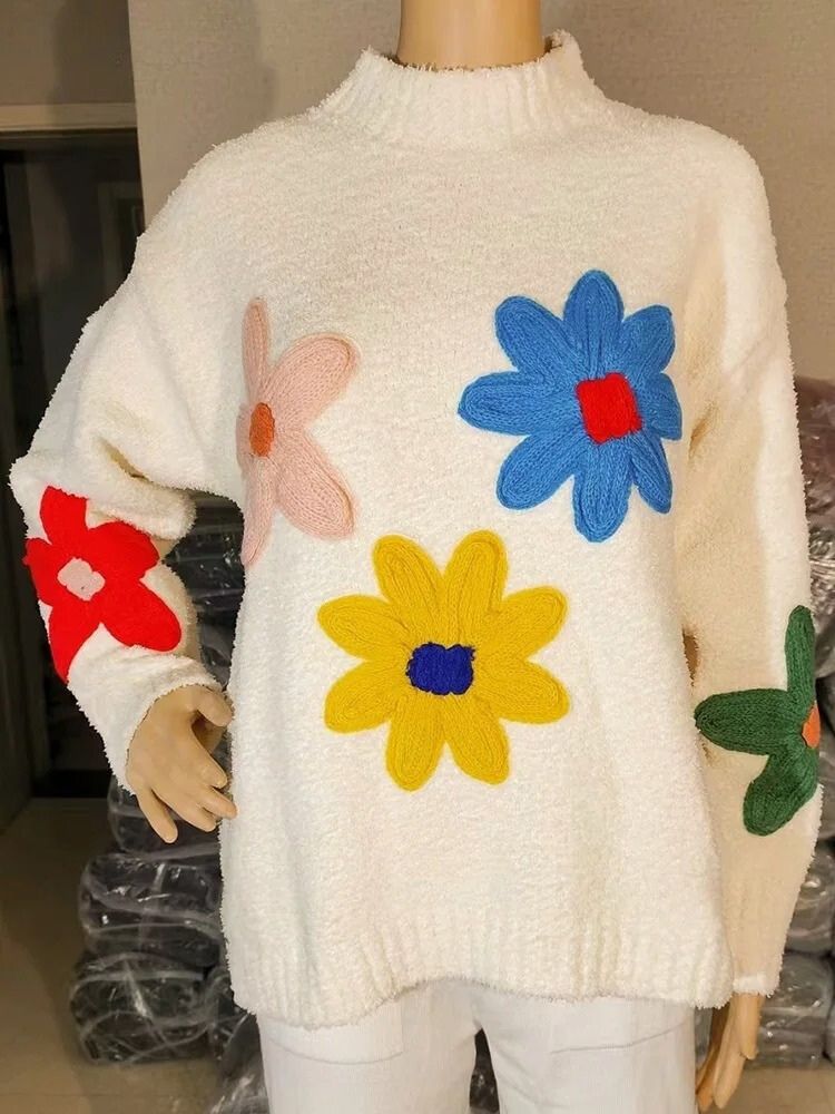 Cream knit sweater with colorful floral appliques displayed on mannequin