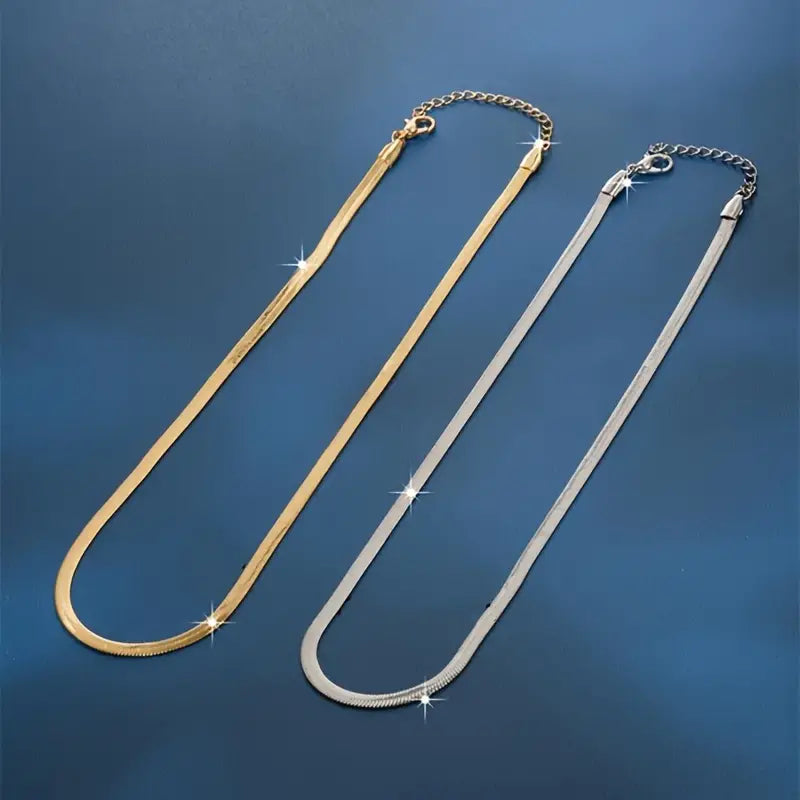 Gold and silver herringbone necklaces side-by-side on blue background