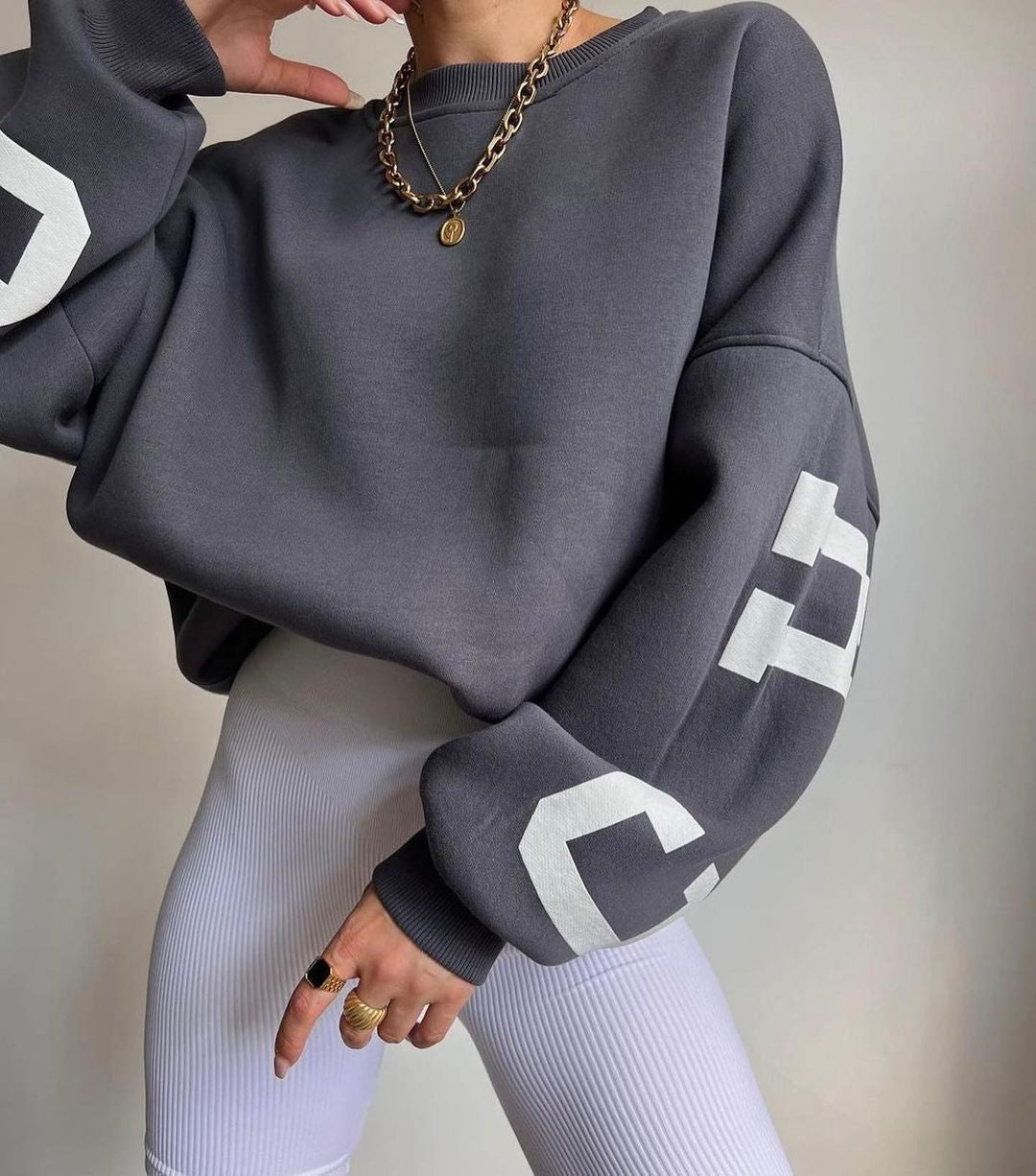Oversized sweater grijs met witte letters, zijprofiel