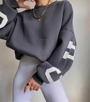 Oversized sweater grijs met witte letters, zijprofiel
