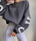 Oversized sweater grijs met witte letters, zijprofiel