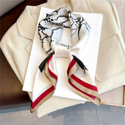 Silk scarf with floral and bird print, red and beige border, folded on white background