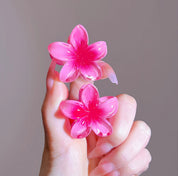 Pink flower-shaped hair clips held in hand.