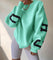 Oversized sweater groen met zwarte letters op mouwen, front view