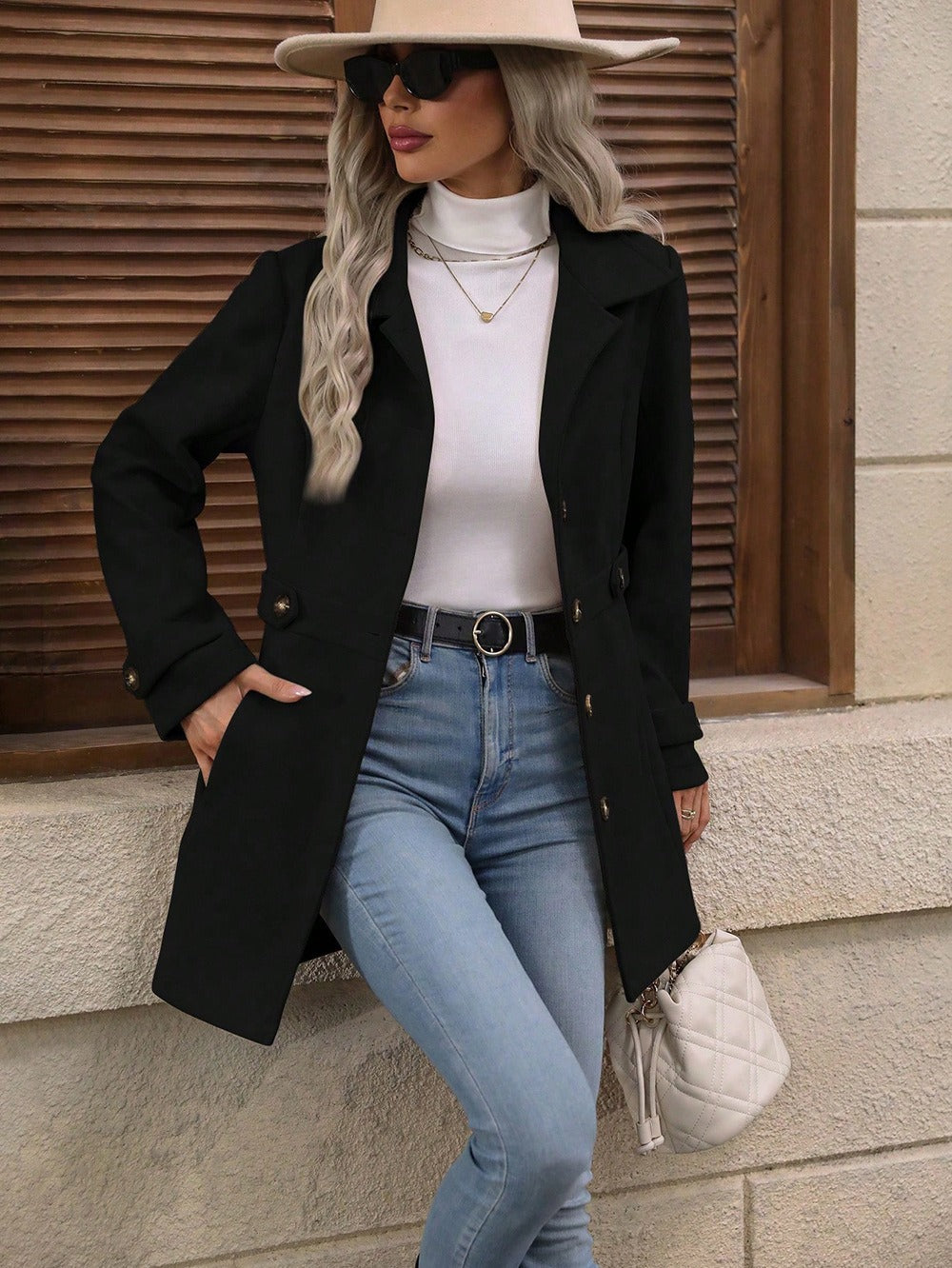 Dames Jas zwart met gouden knopen en riem, model draagt jeans en hoed