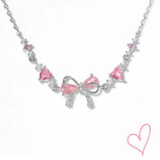 Silver necklace with pink heart stones and bow detail, front view