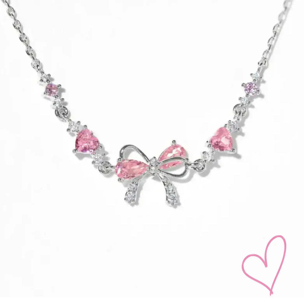 Silver necklace with pink heart stones and bow detail, front view