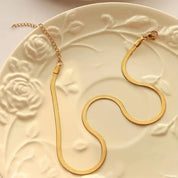 Gold herringbone necklace with clasp on floral plate