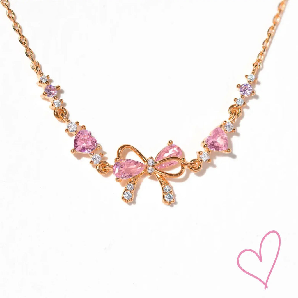 Rose gold necklace with pink heart stones and bow detail, front view