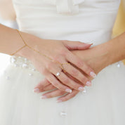 Gold chain bracelet with adjustable design worn on hand with white dress background