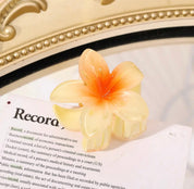 Yellow flower-shaped hair clip with gradient petals on a book page.