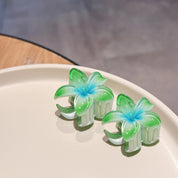 Green and blue flower-shaped hair clips on a beige plate.