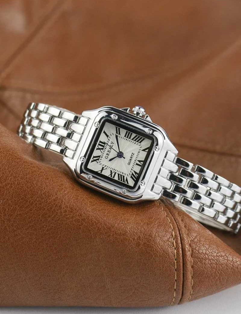 Silver wristwatch with Roman numerals and guilloche dial on brown leather background