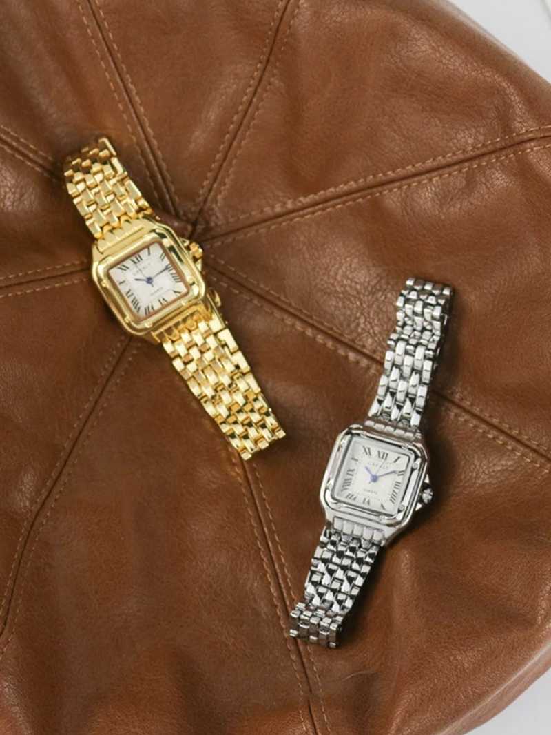Gold and silver wristwatches with Roman numerals and guilloche dials, side-by-side on brown leather background