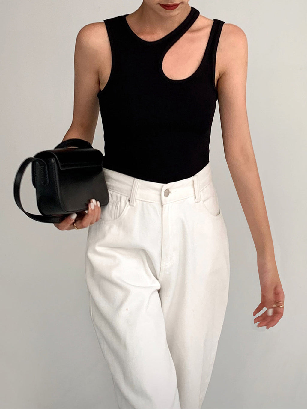 Black tank top with asymmetrical neckline front view with handbag