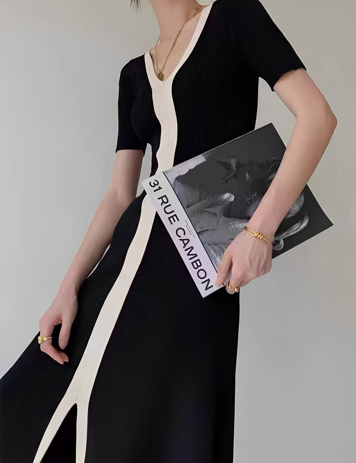 Black and white striped dress with V-neck side view holding magazine