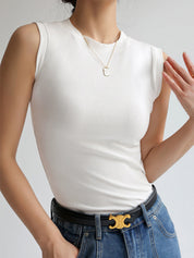 White sleeveless mock-neck top worn with jeans and belt front view