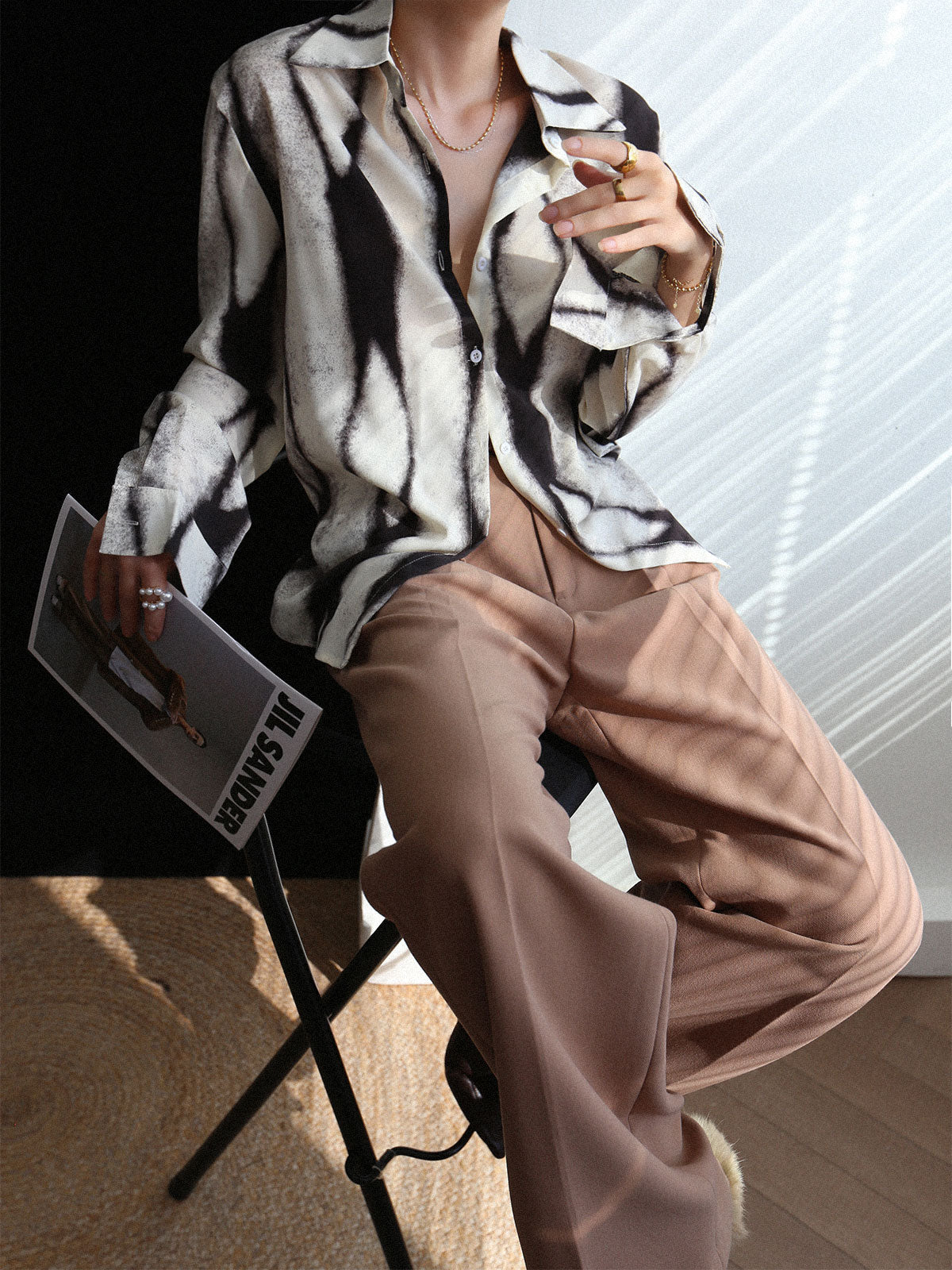 Casual blouse with abstract black and white print, seated pose