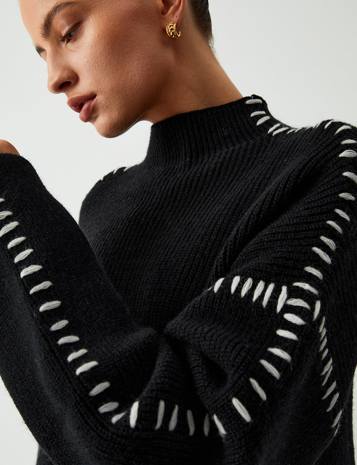 Close-up of black sweater with white dotted trim on sleeves