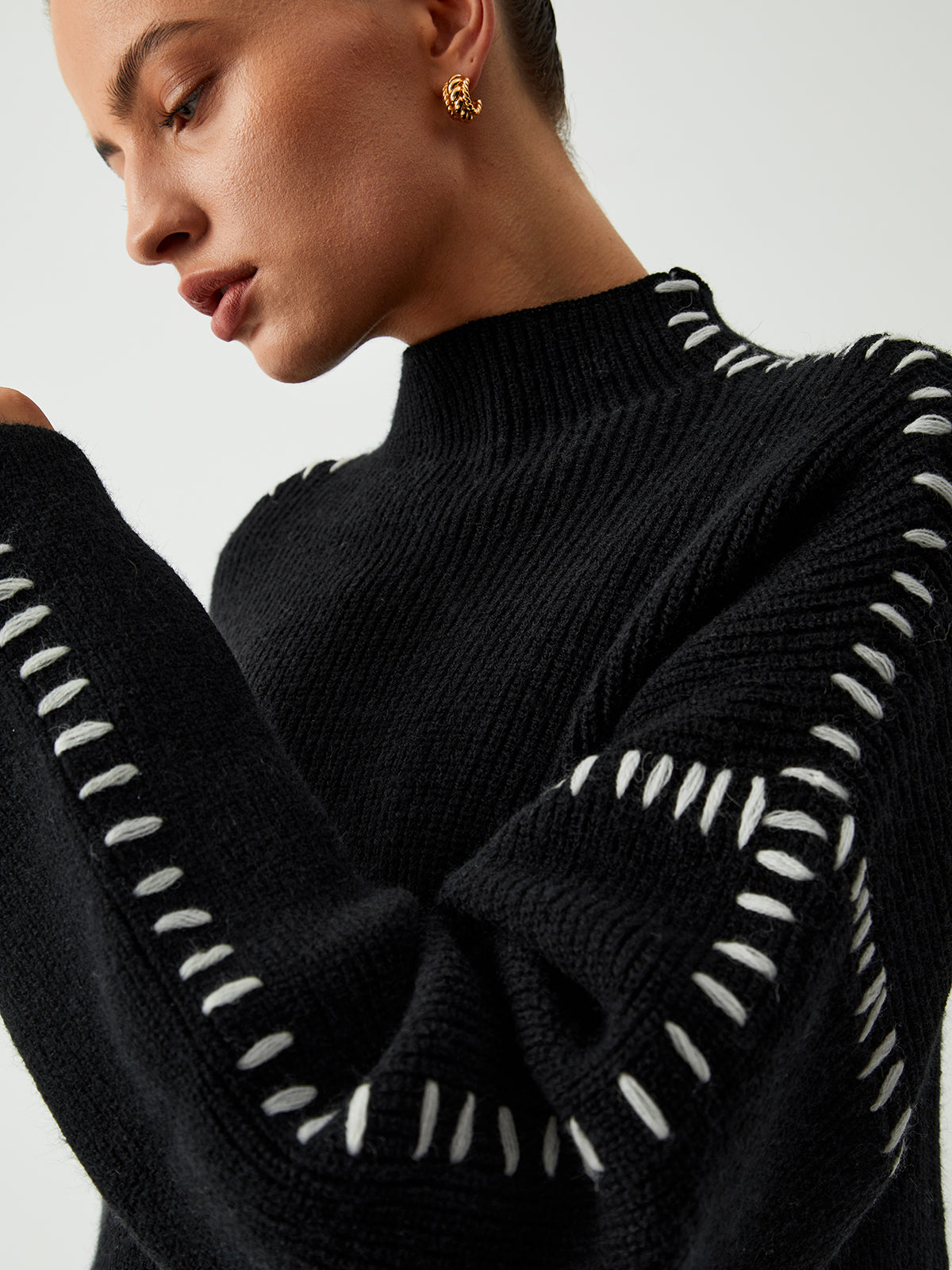 Close-up of black sweater with white dotted trim on sleeves