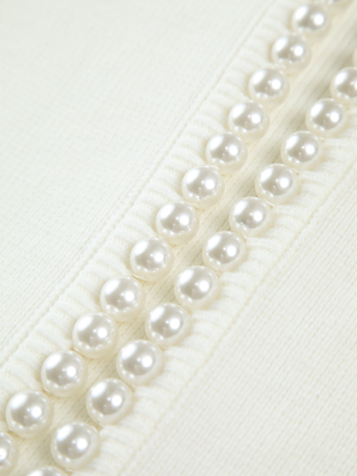 Pearl embellishments on cream cardigan close-up