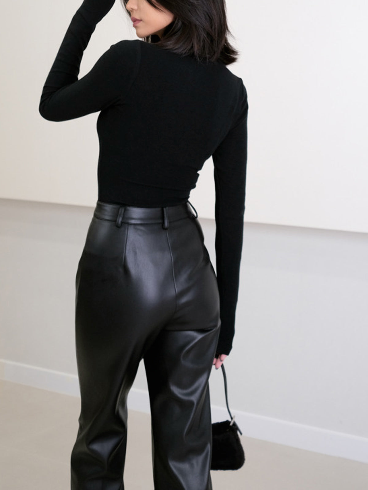 Black faux leather pants back view with handbag
