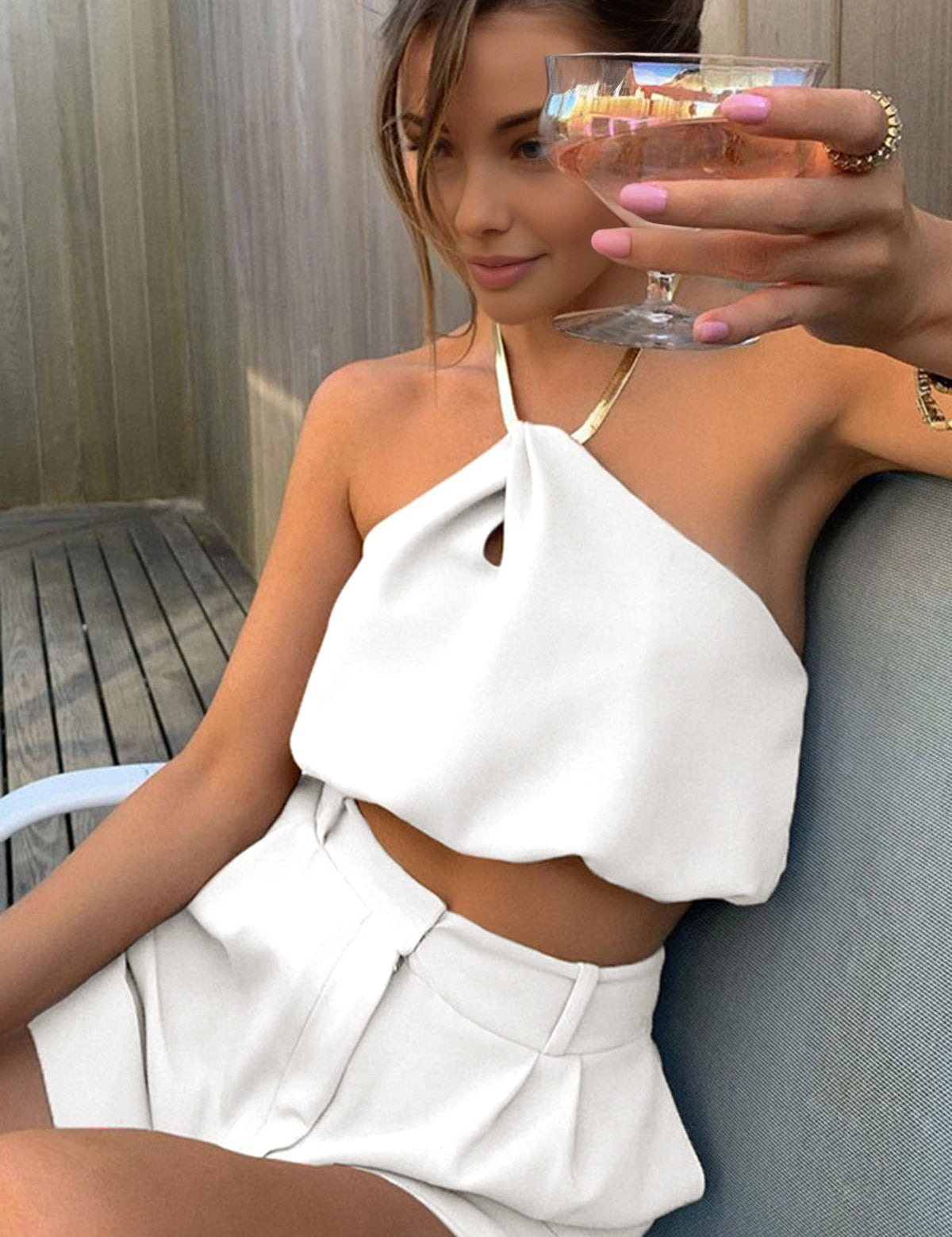 Gold metal necklace on white top and white shorts front view