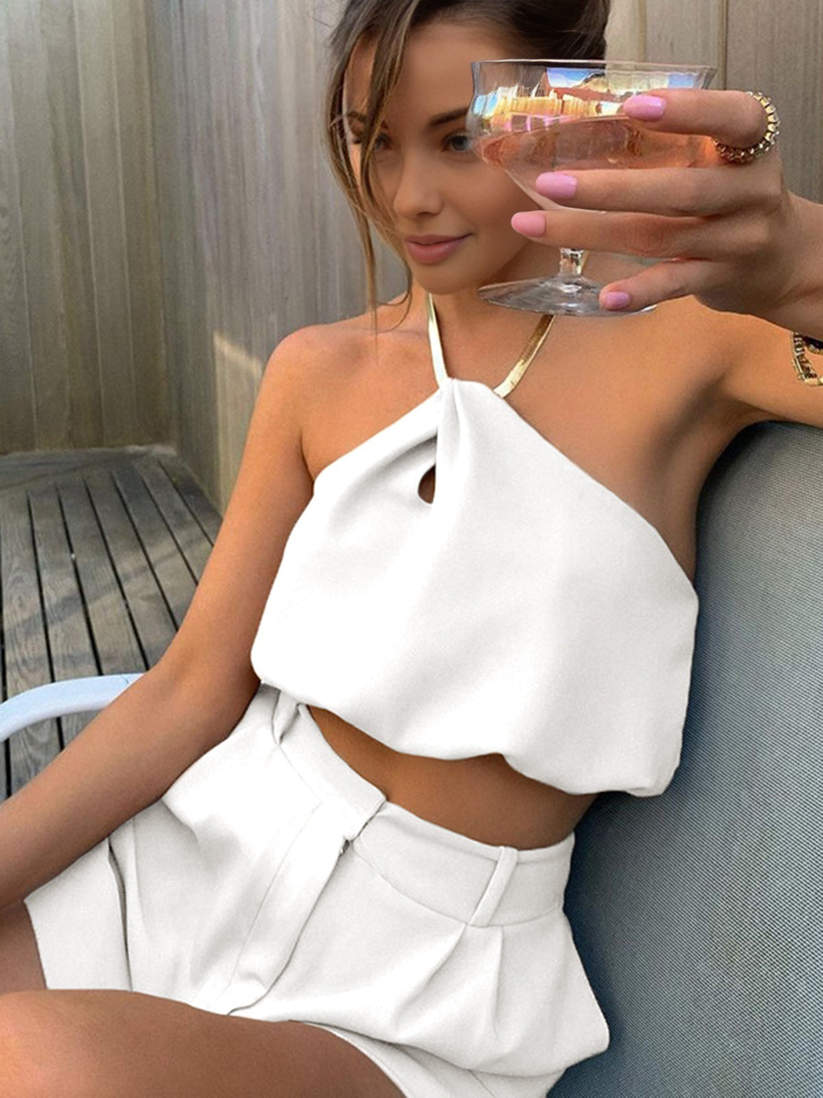 Gold metal necklace on white top and white shorts front view