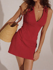 Red V-neck dress with deep neckline and raffia bag front view