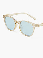 Sunglasses with transparent beige acetate frame and light blue lenses, angled side view