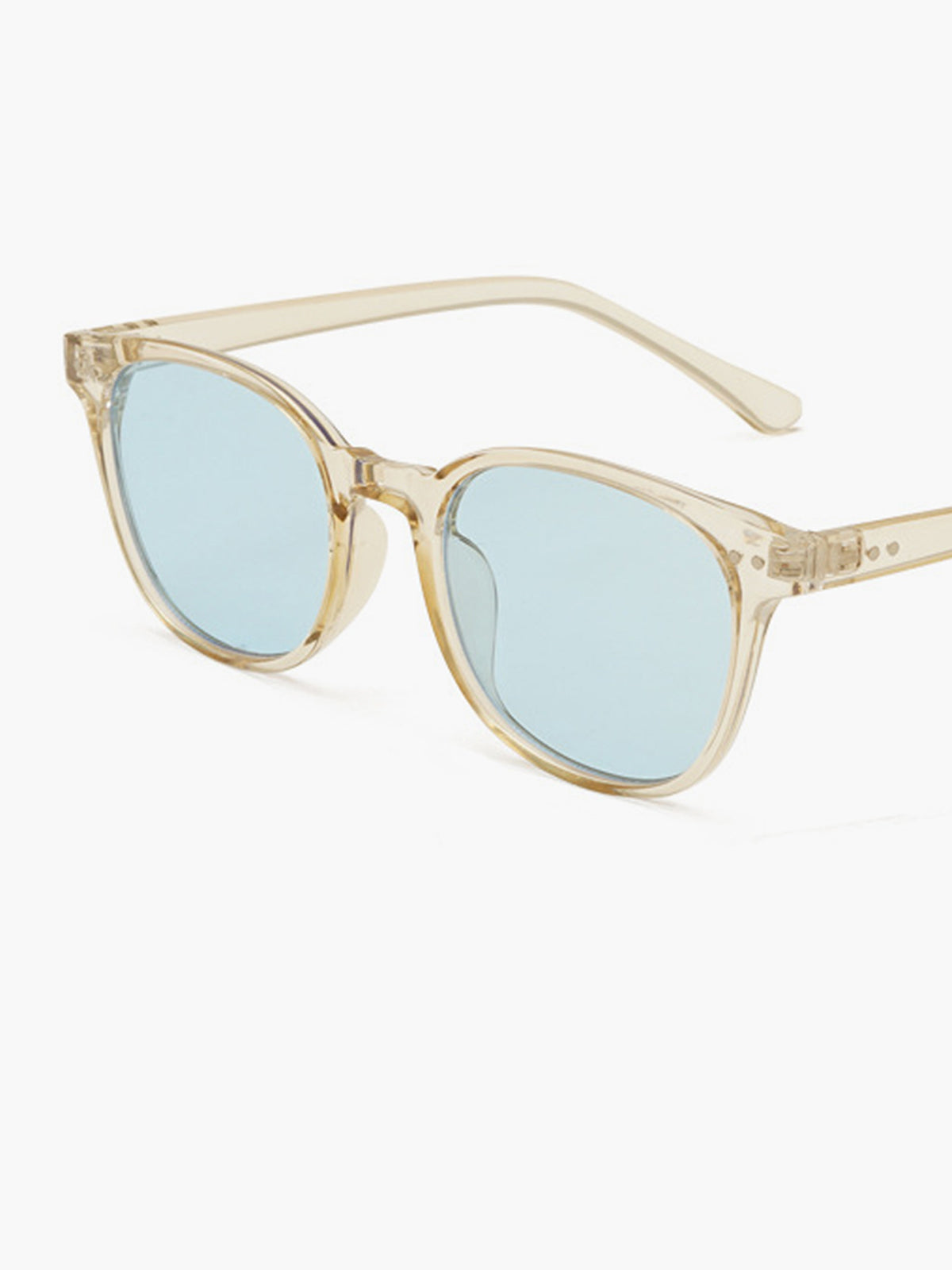 Sunglasses with transparent beige acetate frame and light blue lenses, angled side view