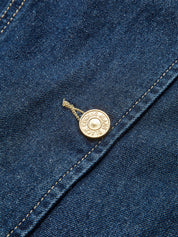 Close-up of gold button on denim fabric with stitching detail