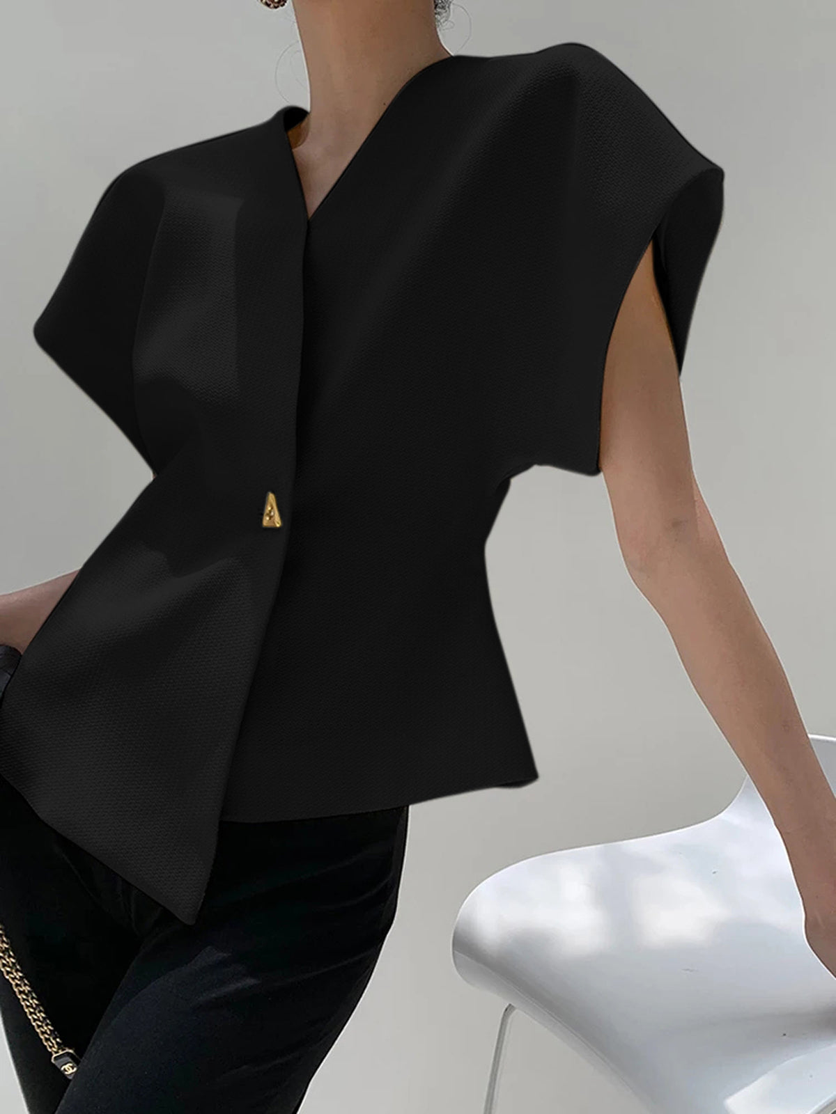 Black V-neck top with gold button detail, side view