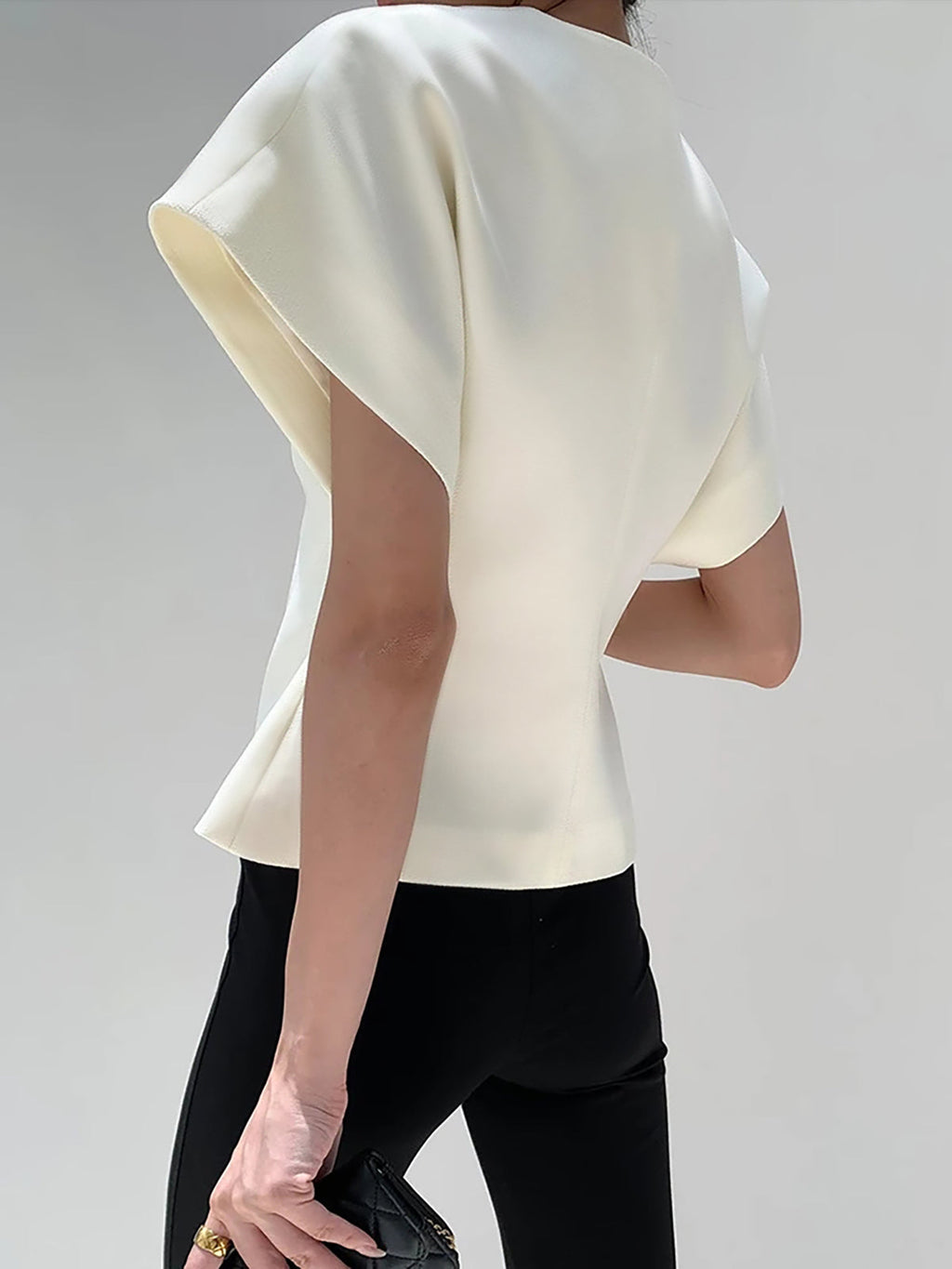 White V-neck top with gold button detail, front view with handbag