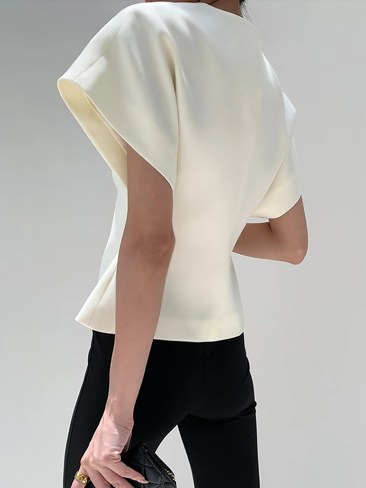 White V-neck top with gold button detail, front view with handbag