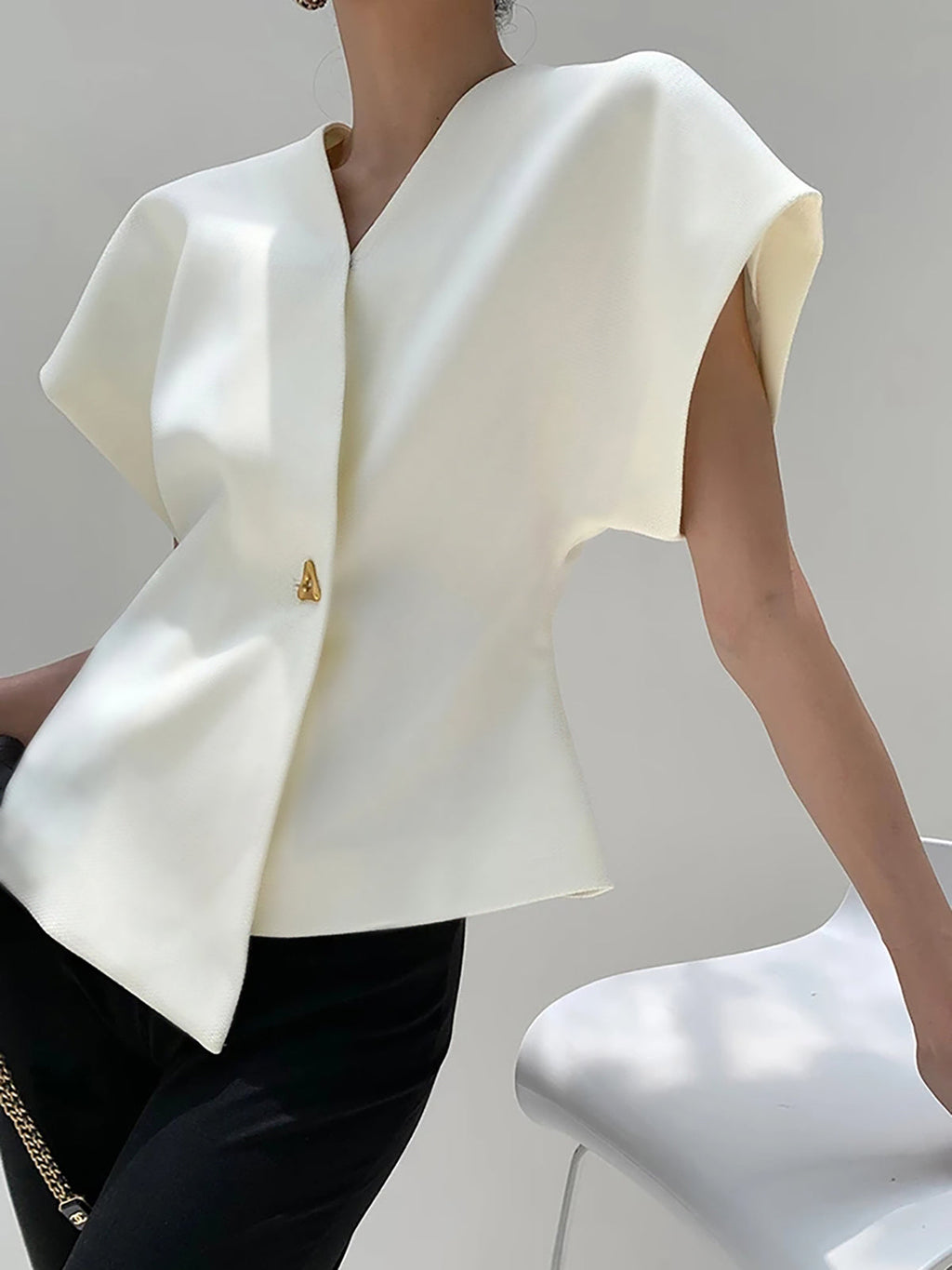 White V-neck top with gold button detail, side view with handbag