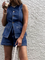 Woman wearing denim playsuit with gold buttons and pockets, holding coffee cup