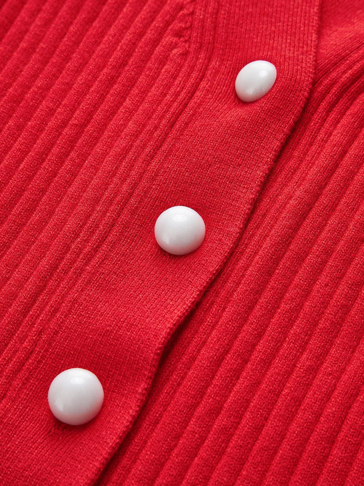 White buttons on red ribbed cardigan close-up