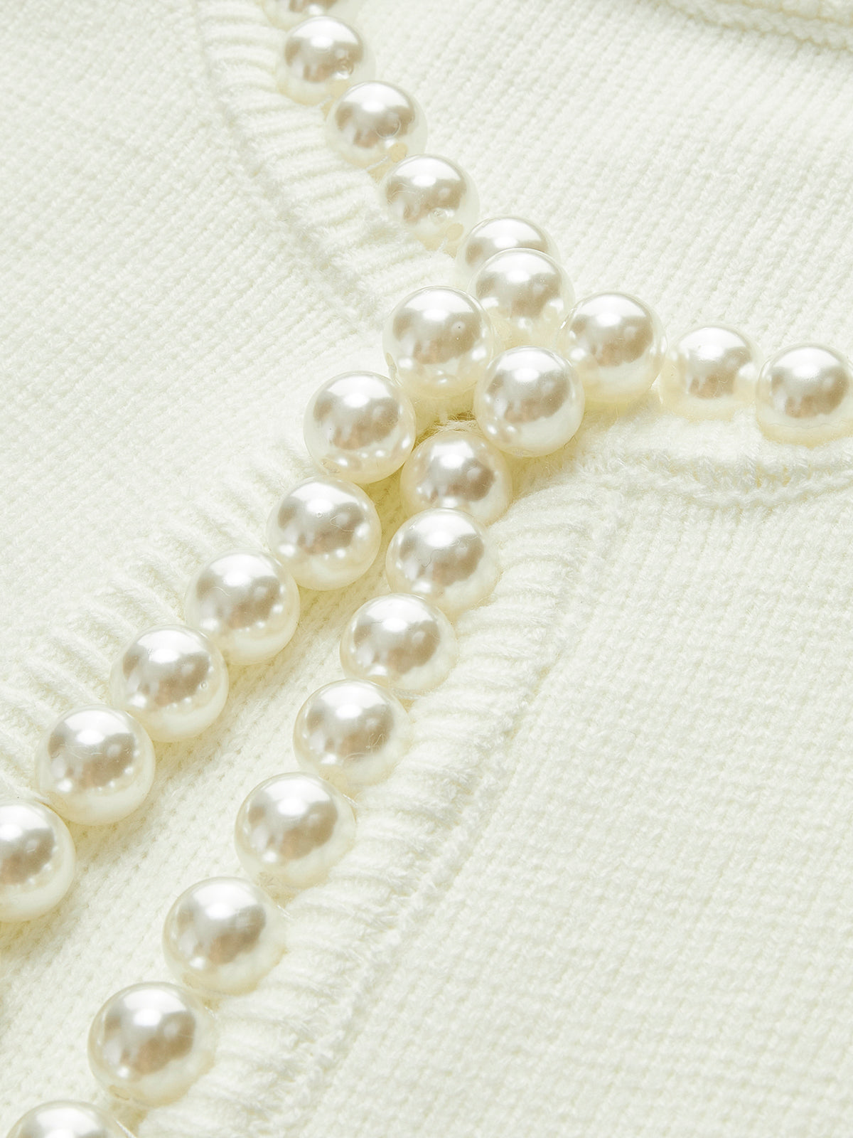 Pearl embellishments on cream cardigan detail shot