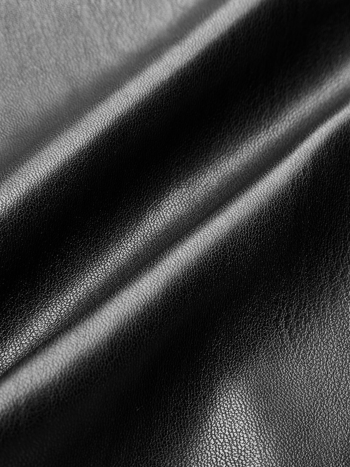 Detail of black faux leather pants fabric folds