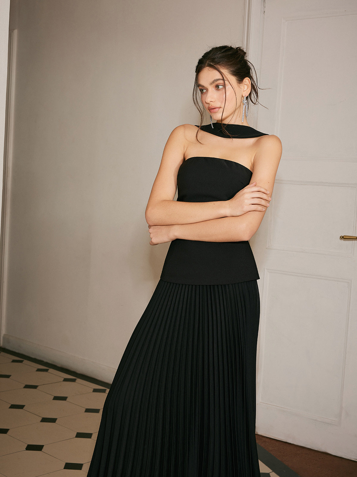Black strapless evening dress with pleated skirt arms crossed