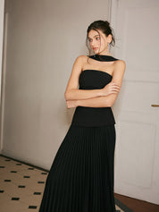 Black strapless evening dress with pleated skirt arms crossed