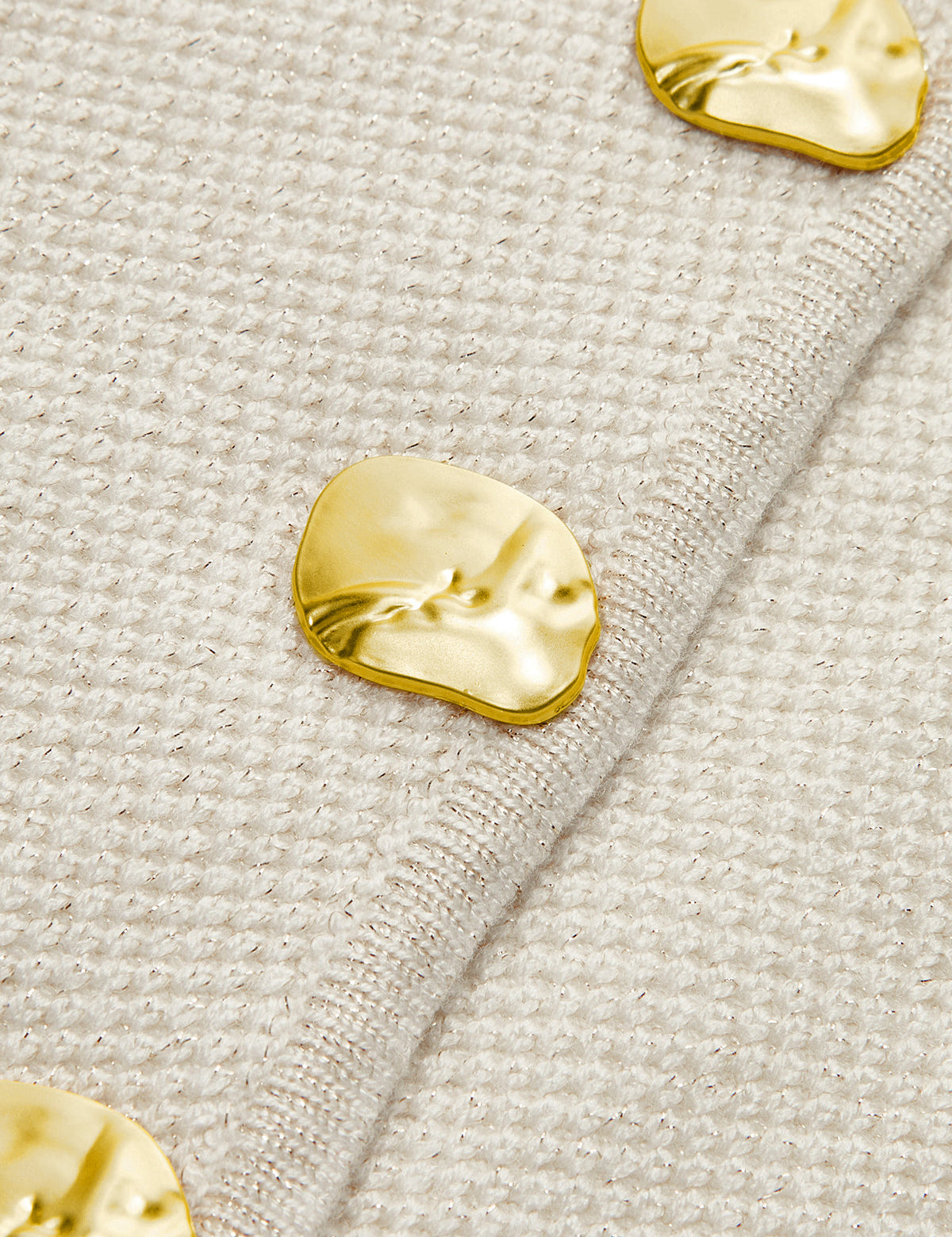 Gold buttons on cream vest close-up