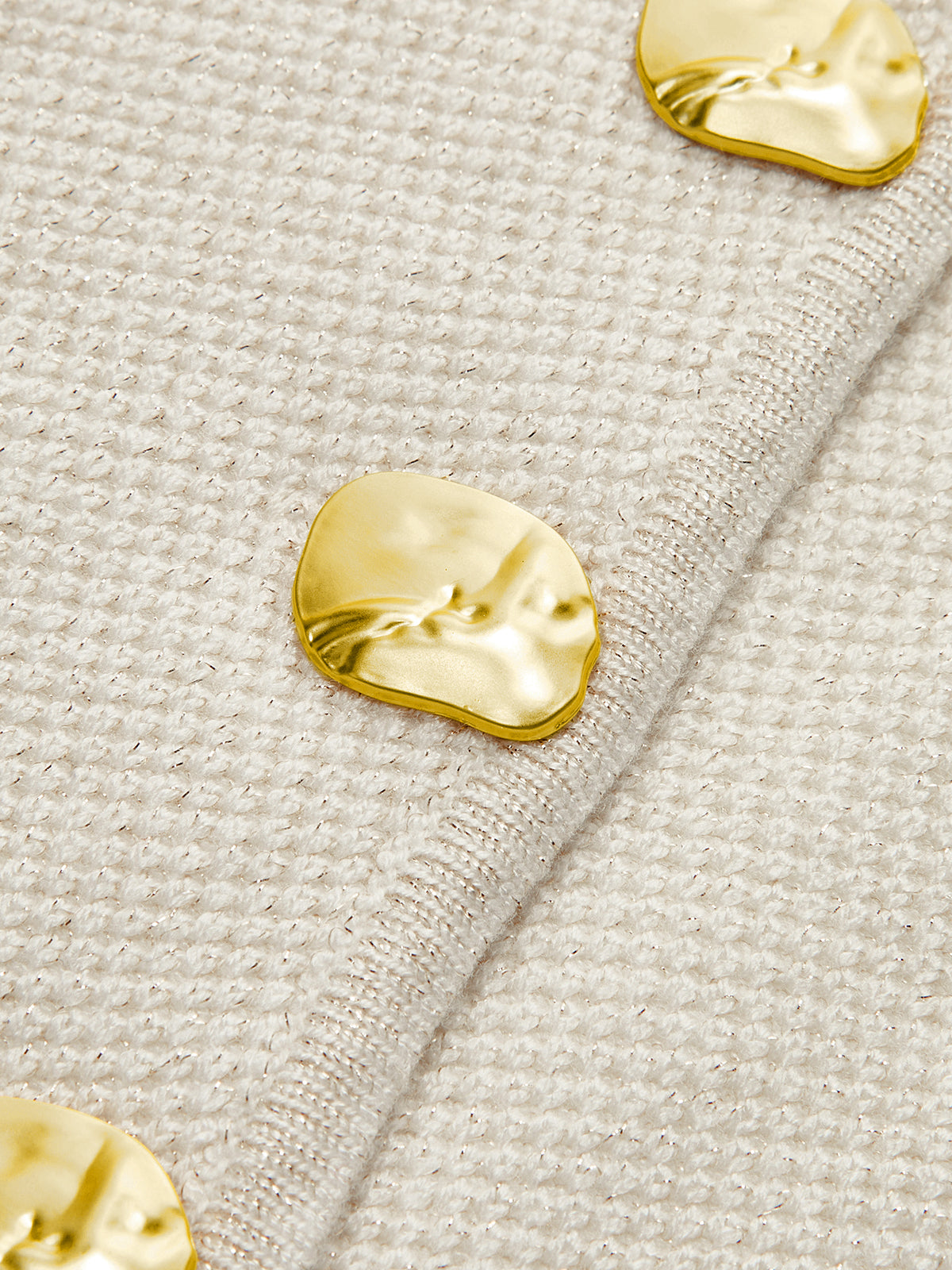 Gold buttons on cream vest close-up